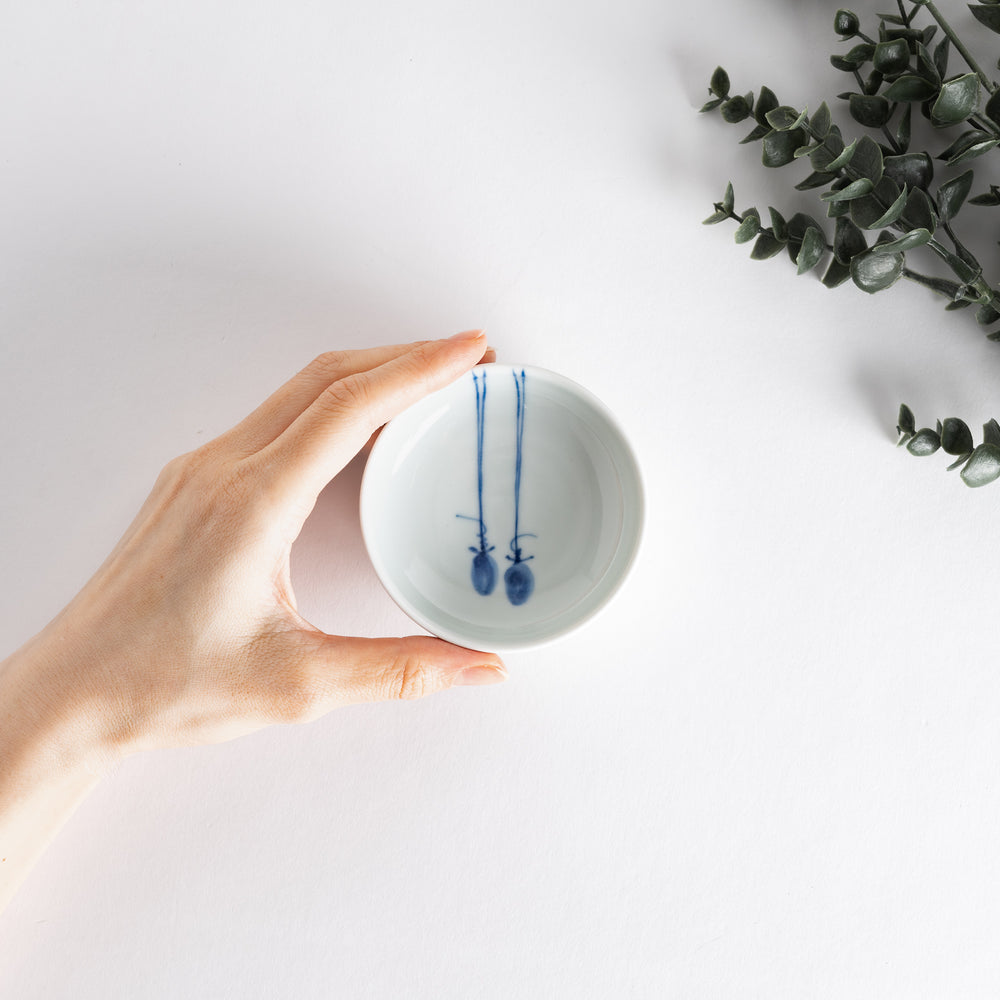 A small porcelain dish with a simple, elegant blue illustration of two persimmons.