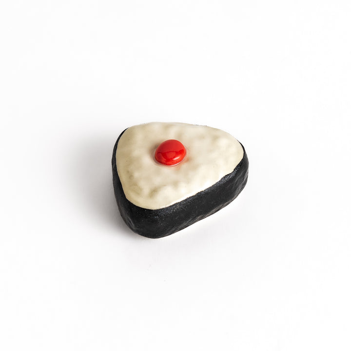 Pickled Plum Onigiri Chopstick Rest featuring a triangular rice ball design with a red plum detail and black seaweed wrap for a playful touch.