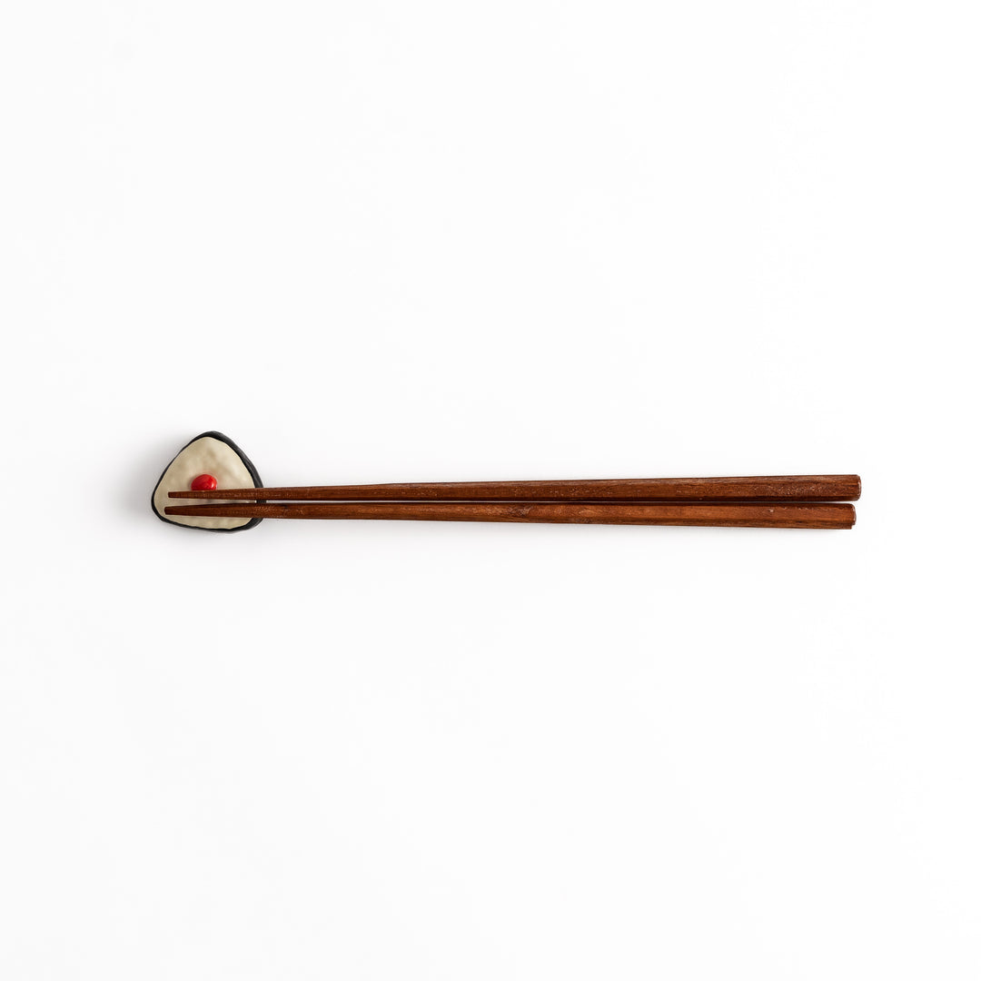 Pickled Plum Onigiri Chopstick Rest holding wooden chopsticks, showcasing its charming rice ball design and practical functionality.