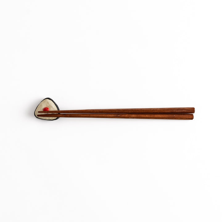 Pickled Plum Onigiri Chopstick Rest holding wooden chopsticks, showcasing its charming rice ball design and practical functionality.