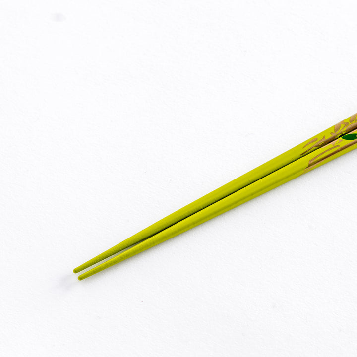 Close-up of the tips of green chopstick with bamboo pattern, highlighting the fine detailing at the end.