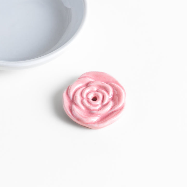 White ceramic incense holder featuring a delicate pink rose-shaped holder, adding an elegant floral touch to incense rituals while enhancing any serene or decorative space.