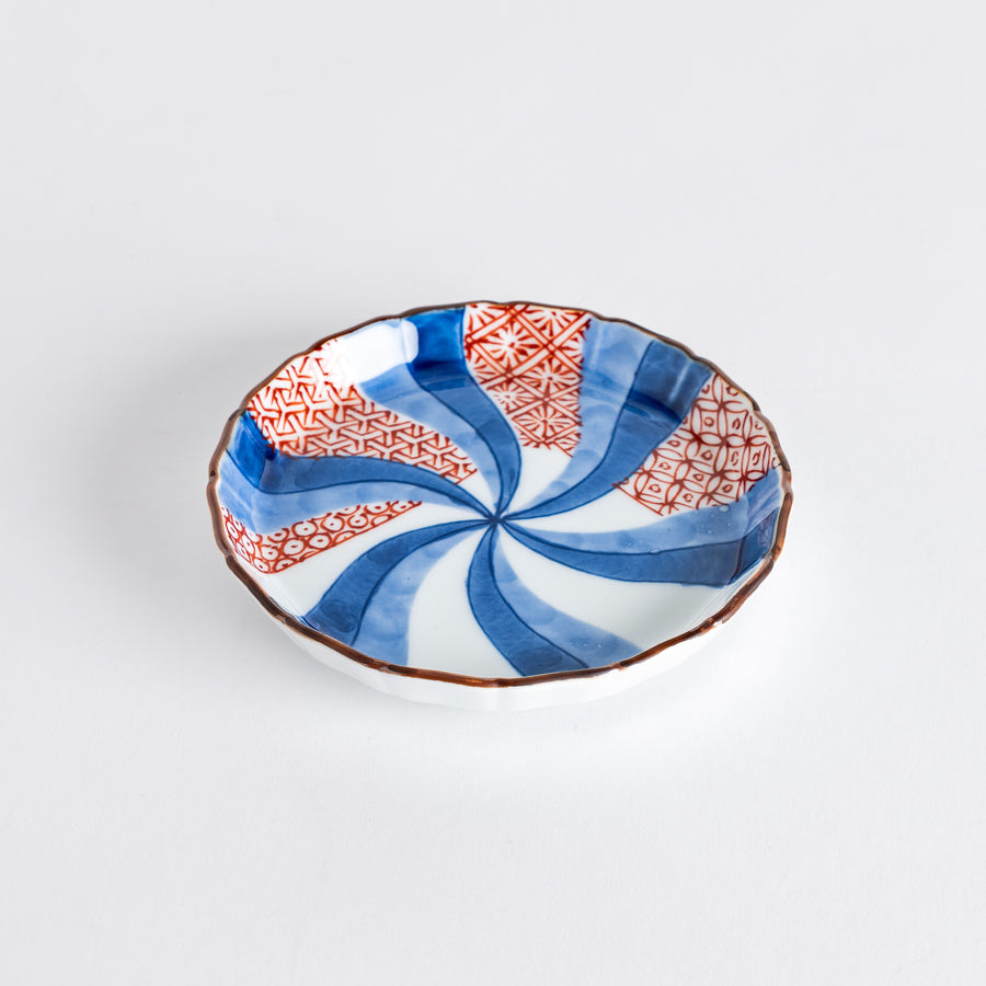 A round plate featuring a bold swirl pattern in red and blue with intricate geometric designs.