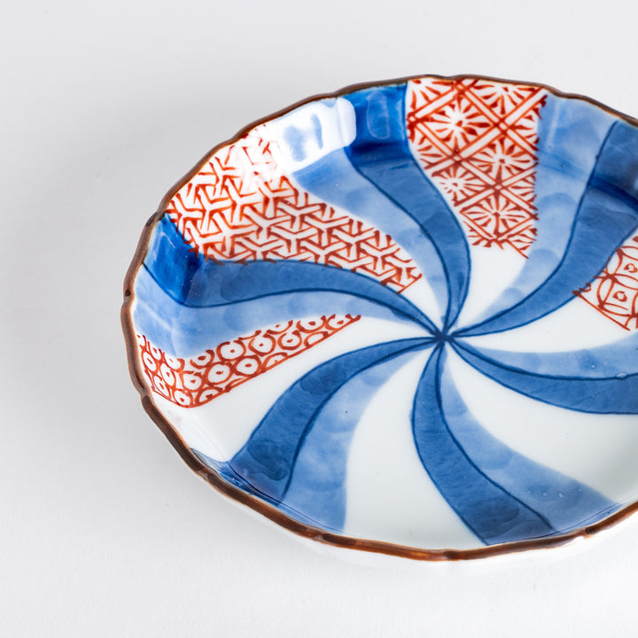 A round plate featuring a bold swirl pattern in red and blue with intricate geometric designs.