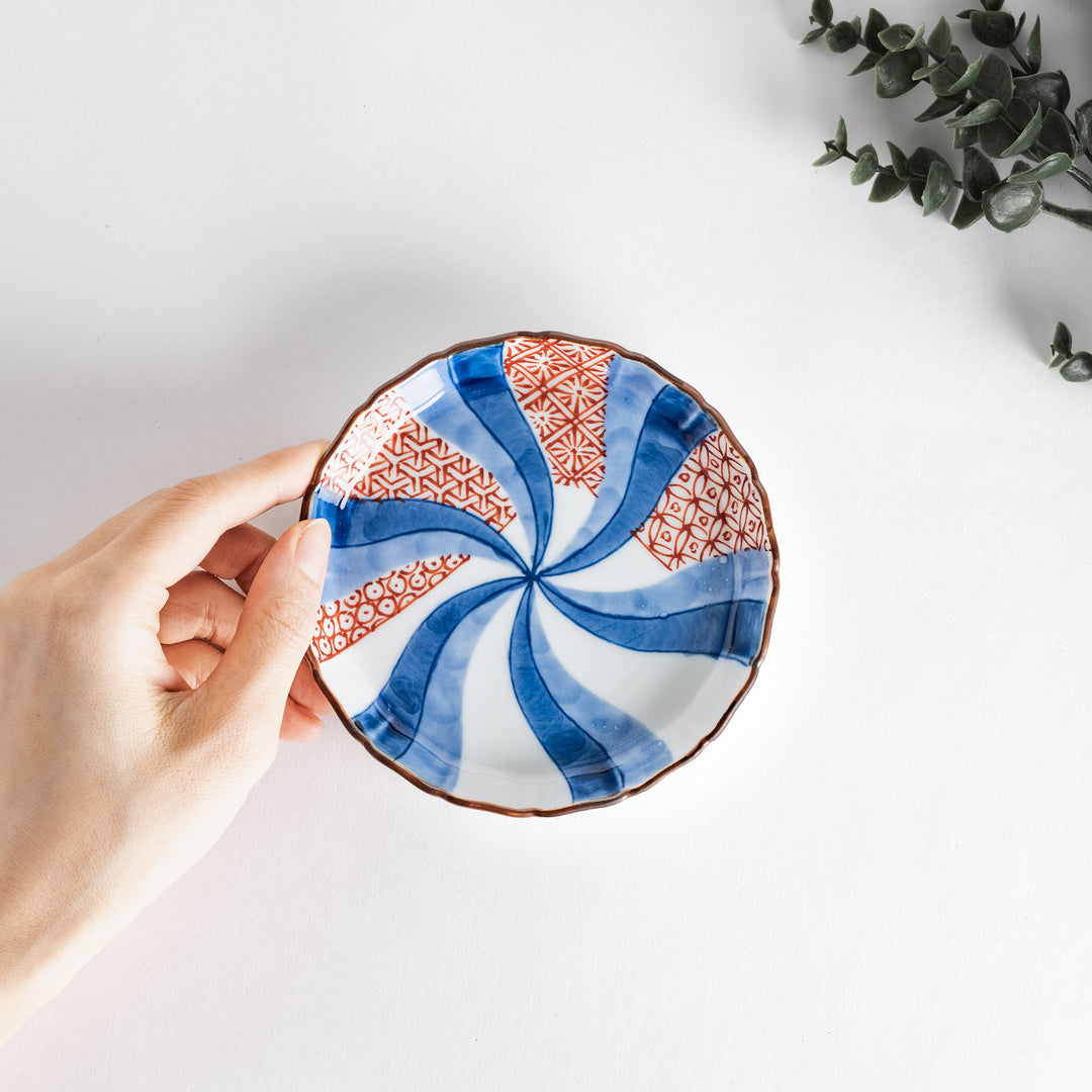 A round plate featuring a bold swirl pattern in red and blue with intricate geometric designs.