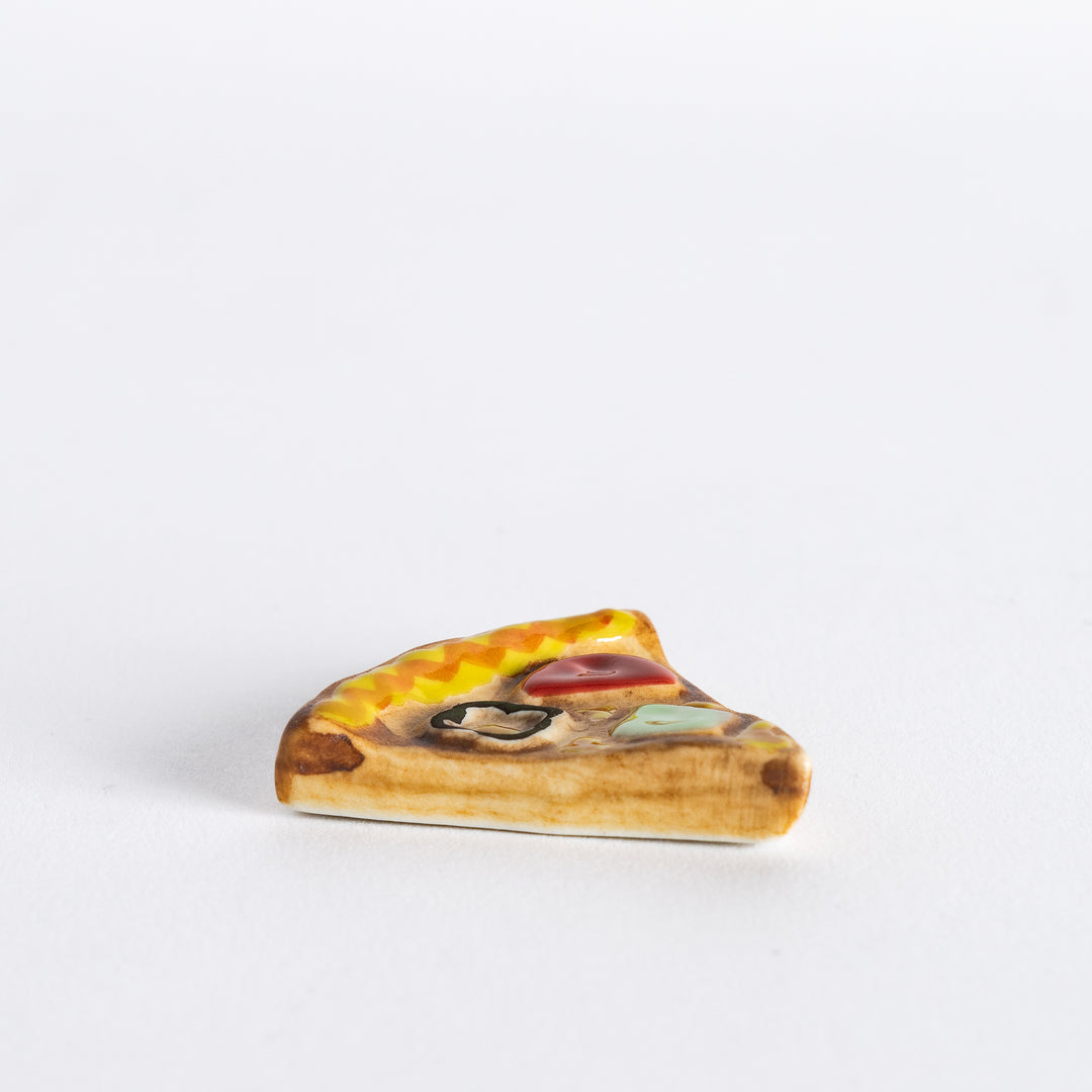 Side view of pizza chopstick rest, displaying the triangular shape and detailed crust.