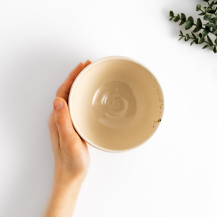 Plum Blossom Matcha Bowl with delicate pink floral designs on a cream-colored surface, perfect for enjoying matcha with a touch of elegance.