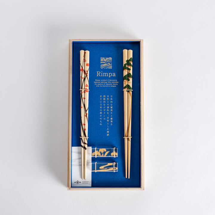 Elegant chopsticks with plum and pine designs, beautifully presented in a wooden box with a blue background.