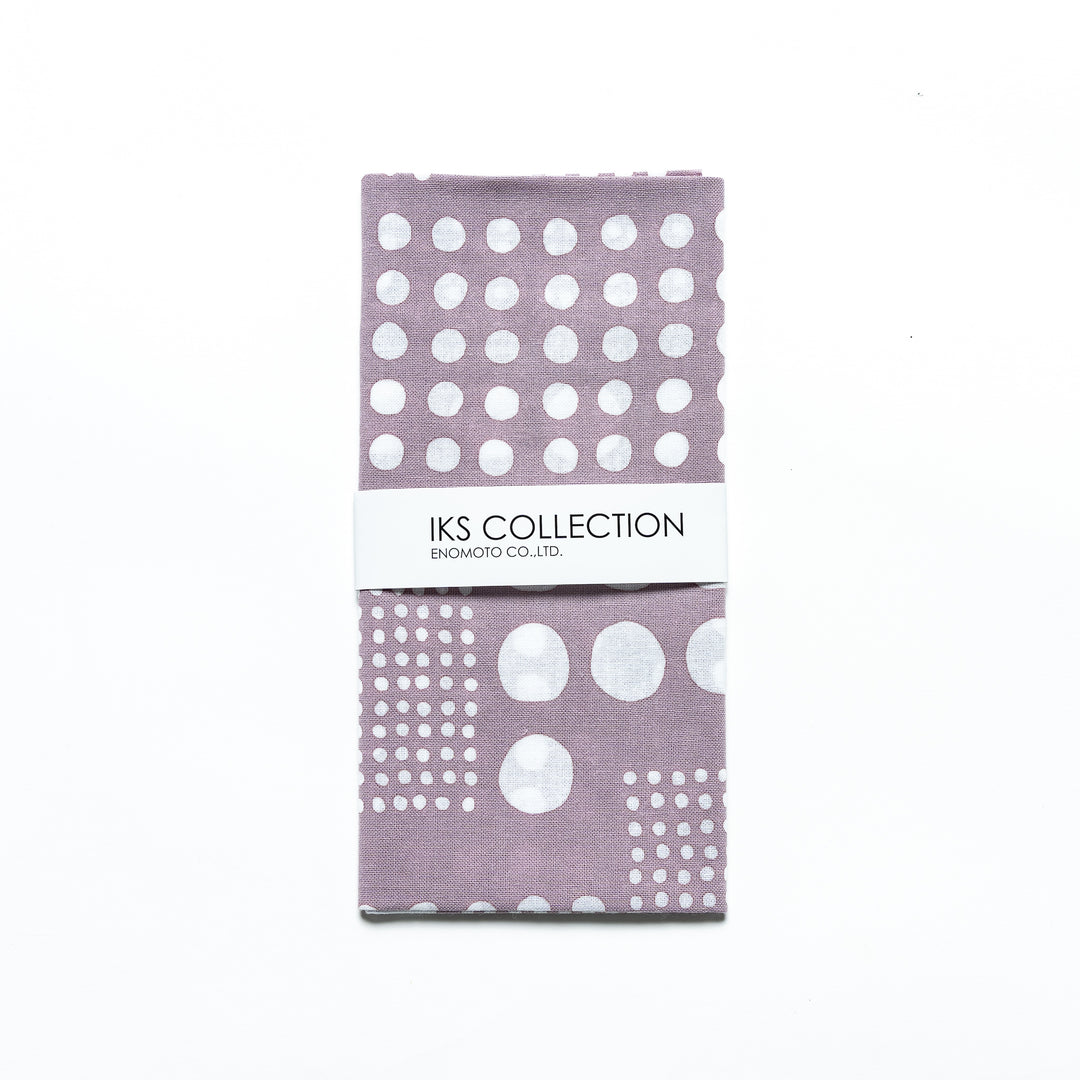 Purple gray polka dot tenugui hand towel folded and wrapped in a product sleeve for display.