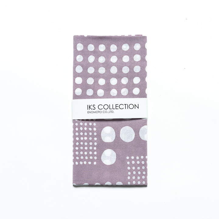 Purple gray polka dot tenugui hand towel folded and wrapped in a product sleeve for display.