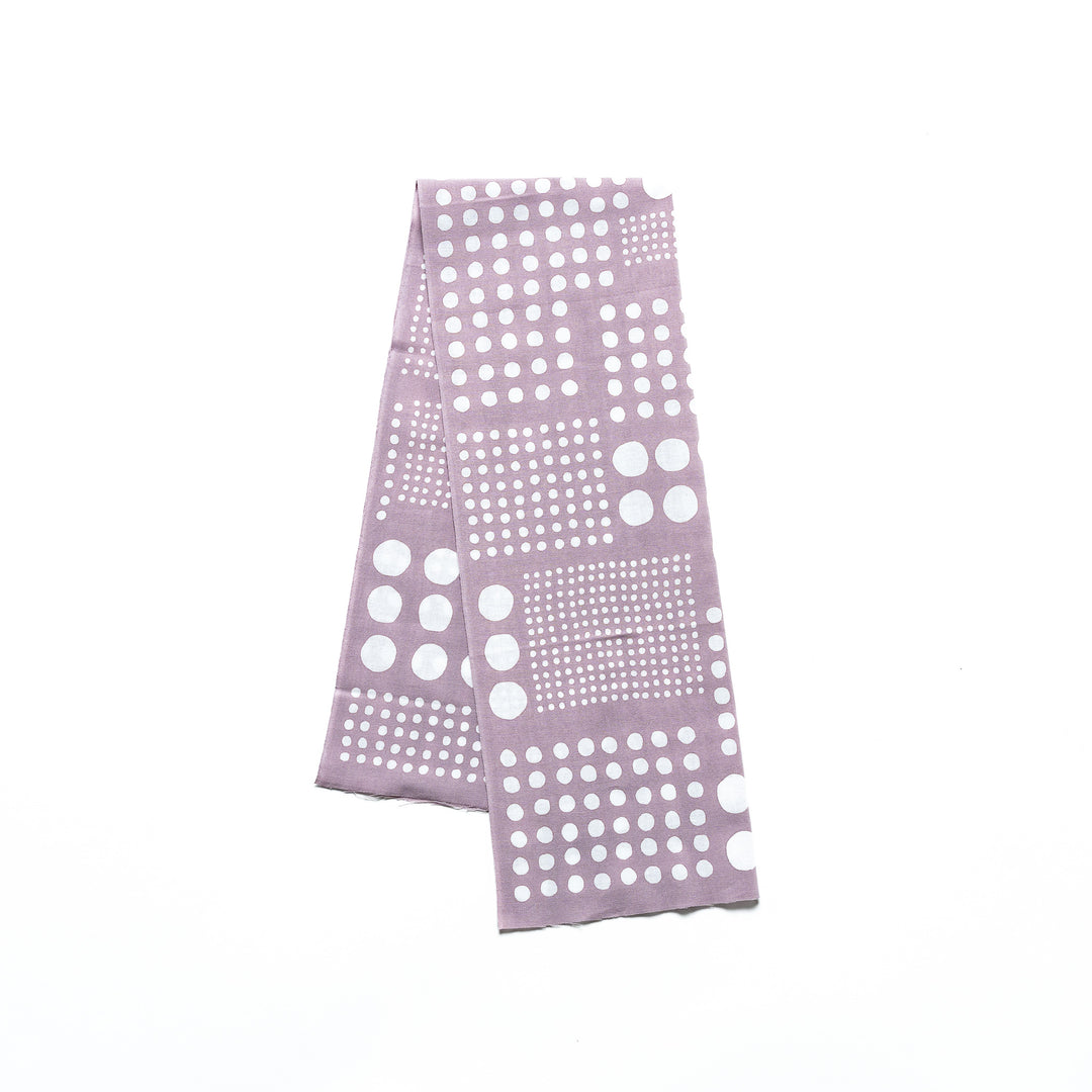 Polka dot tenugui hand towel in purple gray with white dots, folded neatly against a plain background.