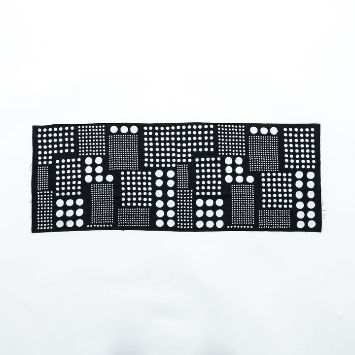 Polka dot tenugui hand towel laid flat, showcasing an arrangement of white dots on black fabric.