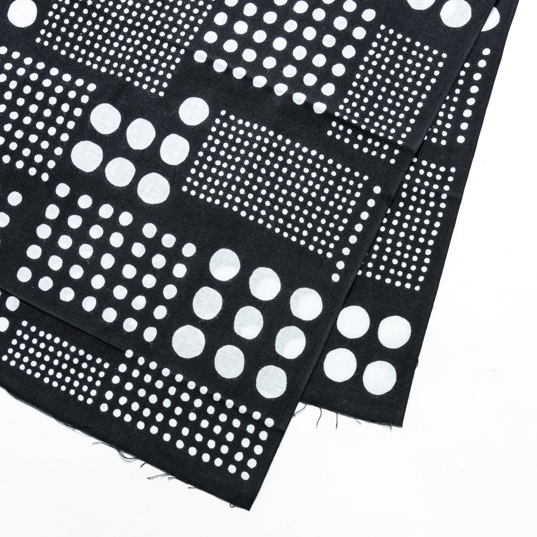 Close-up of black tenugui hand towel highlighting the white polka dot pattern in square arrangements.