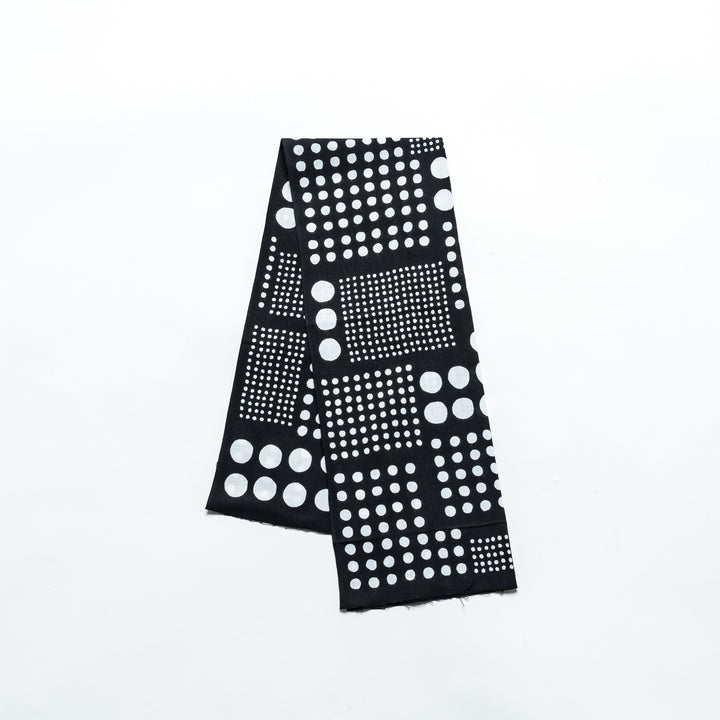 Polka dot tenugui hand towel in black with white dots, folded neatly against a plain background.