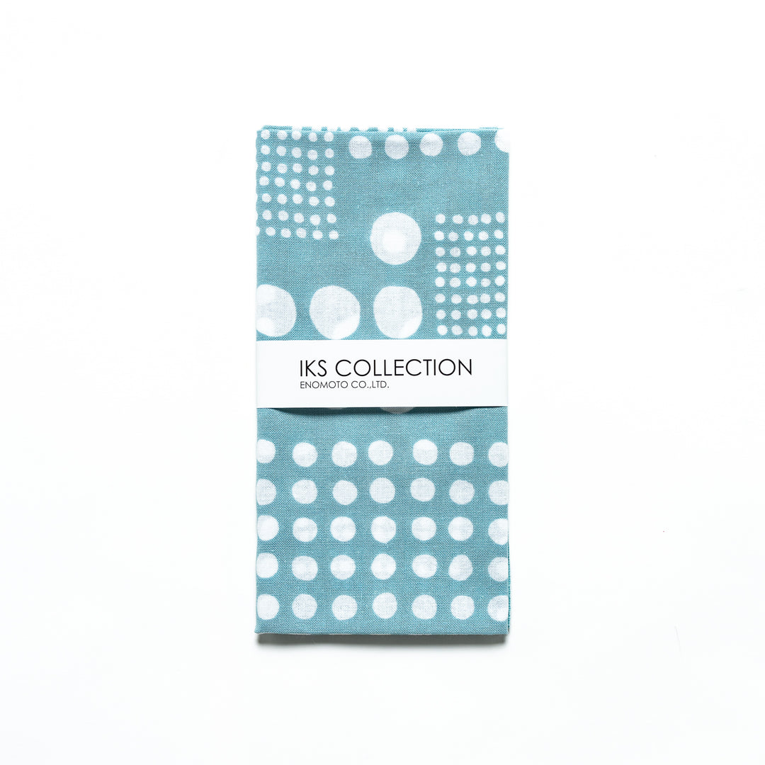 Blue polka dot tenugui hand towel folded with a product sleeve for display.