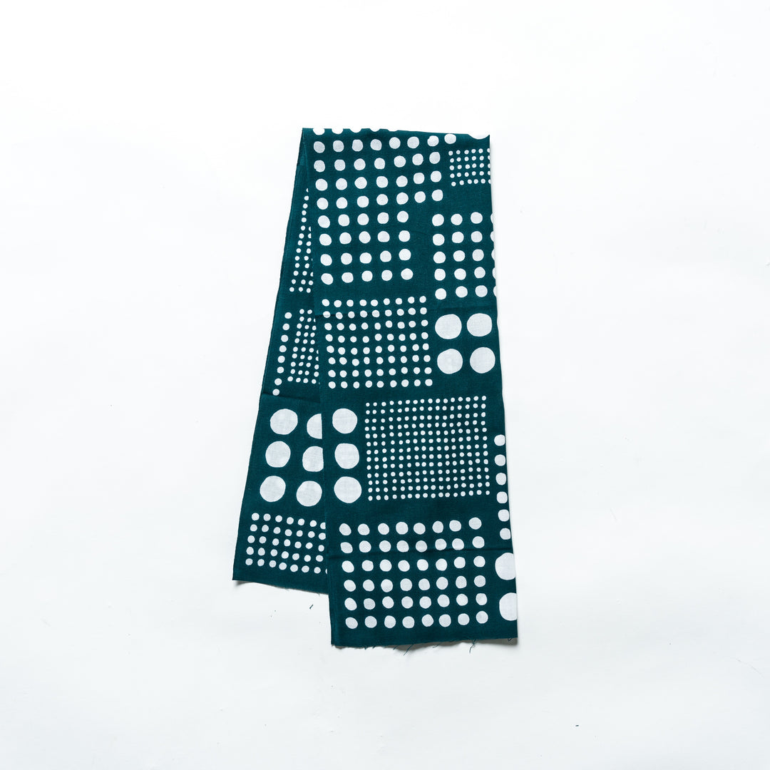 Polka dot tenugui hand towel in green with white dots, folded neatly against a plain background.