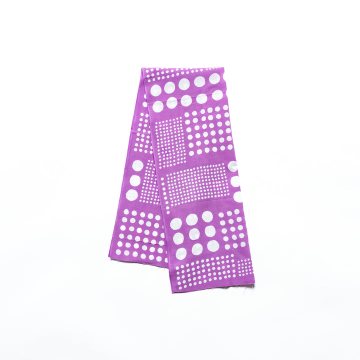 Polka dot tenugui hand towel in purple with white dots, folded neatly against a plain background.