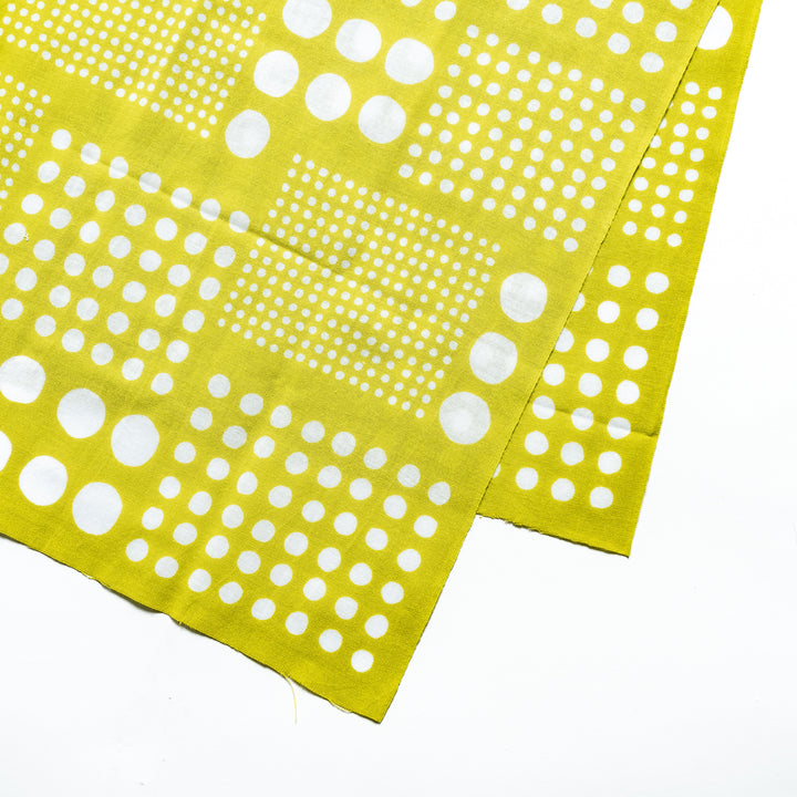 Close-up of yellow green tenugui hand towel highlighting the intricate white polka dot pattern.