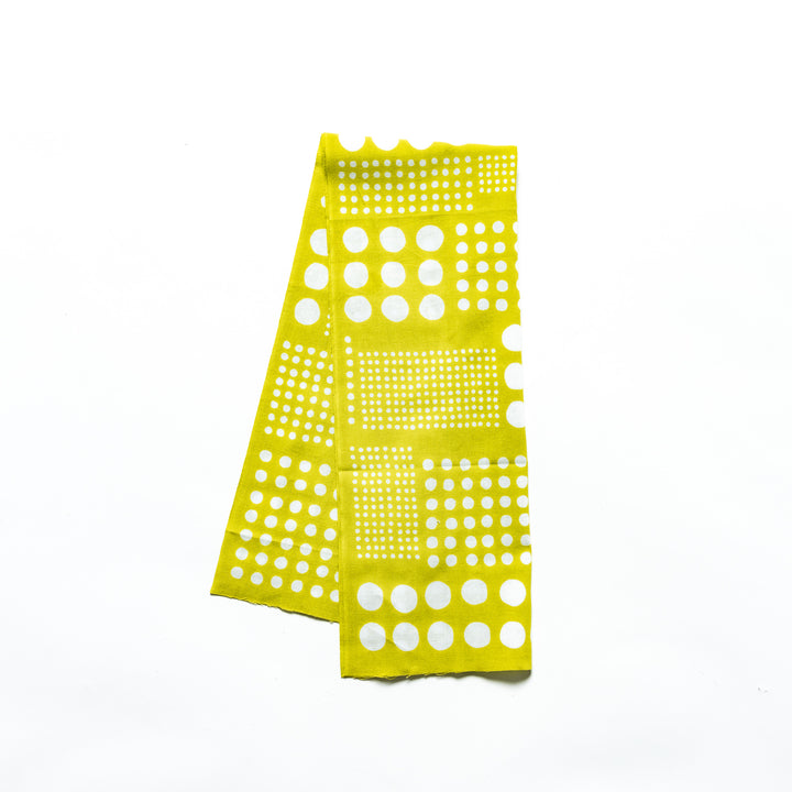 Polka dot tenugui hand towel in yellow green with white dots, folded neatly against a plain background.