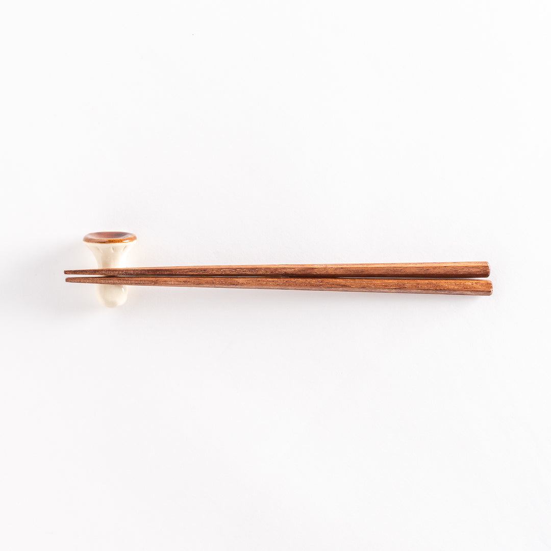 Porcini mushroom chopsticks rest with chopsticks placed on top, photographed from a distance.