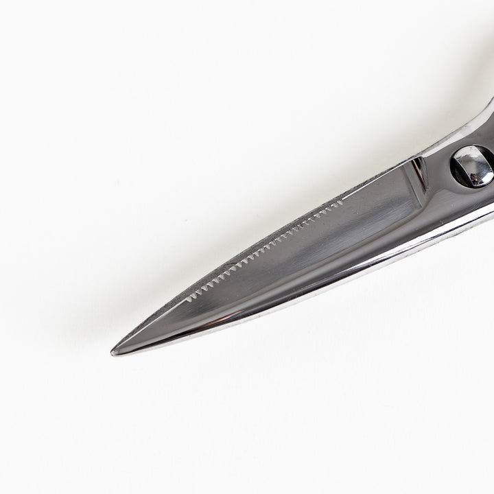 Close-up of the serrated stainless steel blades on kitchen shears, designed for precise and efficient cutting of various foods.