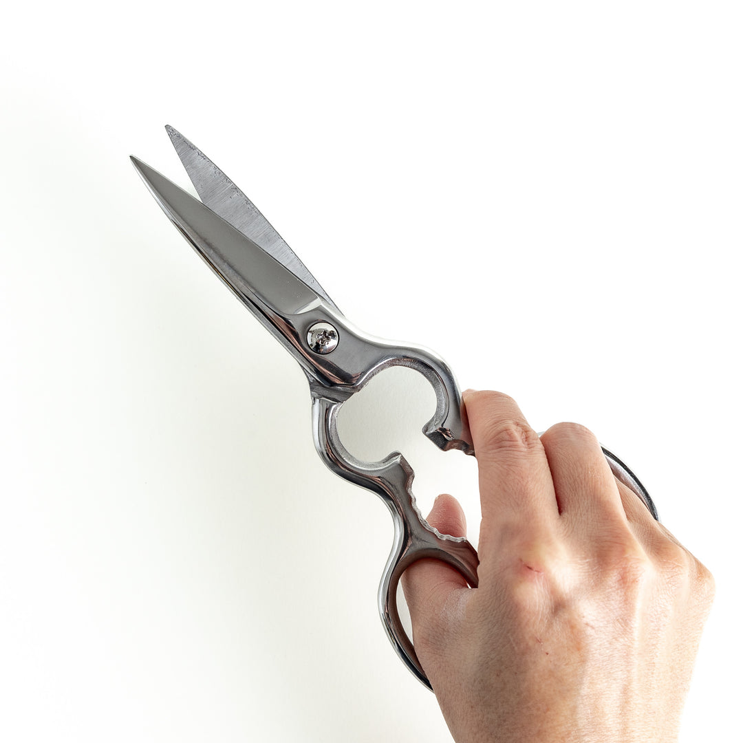 Close-up view of kitchen shears gripped, highlighting the sturdy design and comfort for effortless use during meal prep.