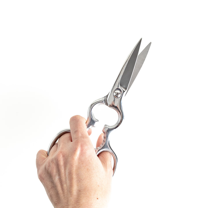 Kitchen shears in hand, demonstrating sharp blades and a comfortable grip for efficient cutting.