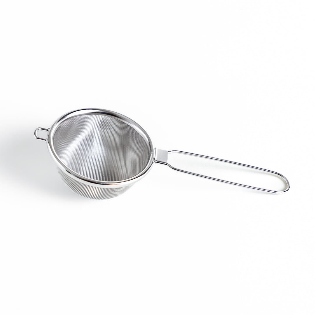 Stainless steel tea strainer with a fine mesh and a long handle, an essential kitchenware tool for brewing loose leaf tea.