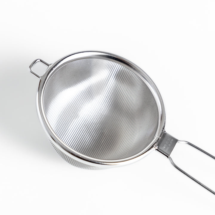 Stainless steel tea strainer with a fine mesh and a long handle, an essential kitchenware tool for brewing loose leaf tea.