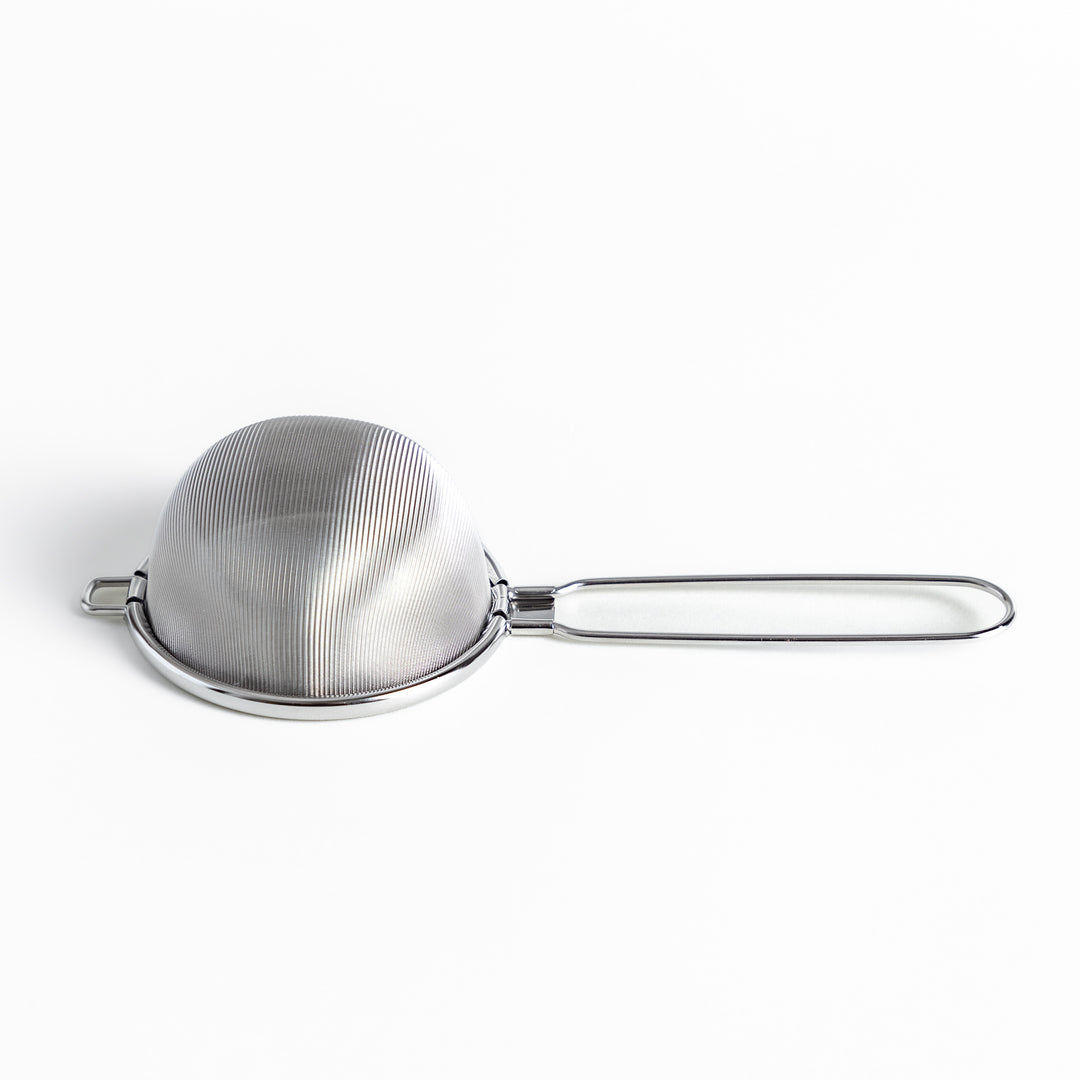 Stainless steel tea strainer with a fine mesh and a long handle, an essential kitchenware tool for brewing loose leaf tea.