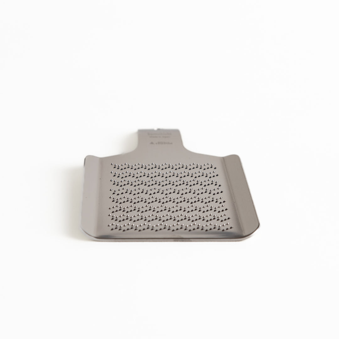 Stainless steel wasabi grater with a unique wave pattern, a specialized kitchenware tool for finely grating fresh wasabi root.