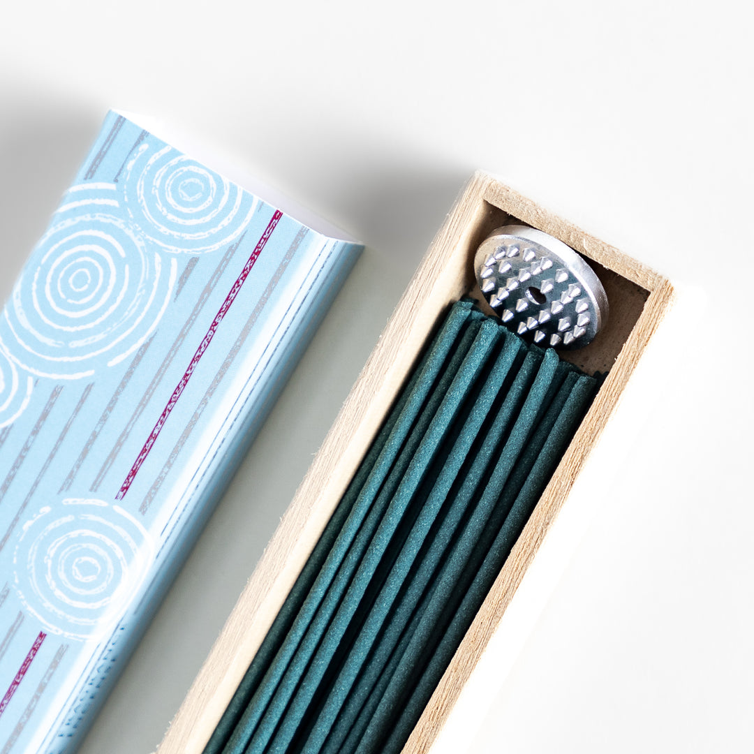 Radiant Jasmine Incense in a light wooden box with deep teal sticks, elegantly packaged in a soft blue design featuring white circular patterns for a fresh and floral ambiance.