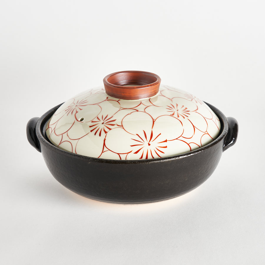 A black donabe with a white lid featuring a red floral design, showing the lid and body together.