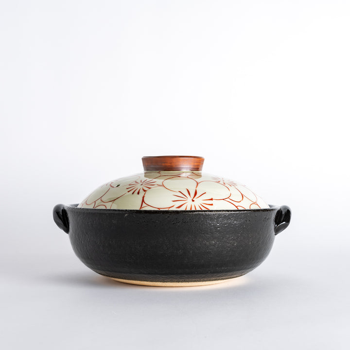 A donabe with a vibrant red floral pattern on white lid and black pot.