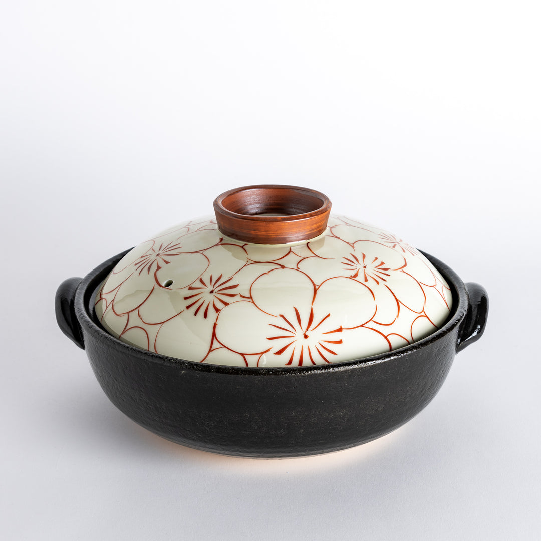 A donabe with a vibrant red floral pattern on white lid and black pot.