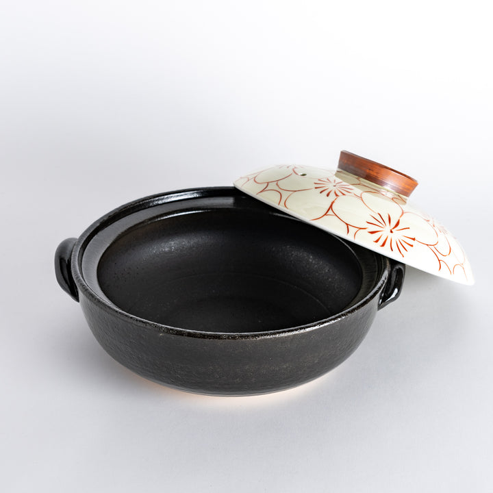 A donabe with a vibrant red floral pattern on white lid and black pot.