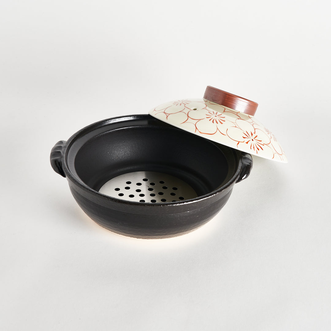 Black donabe with a red blossom-patterned lid partially removed, revealing the metal vent plate inside the pot.