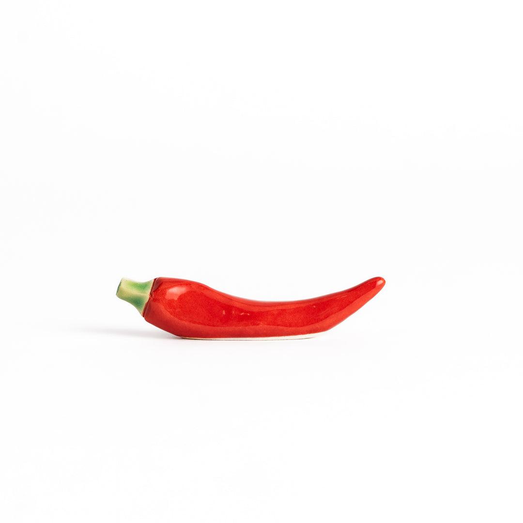 Red chili pepper-shaped chopstick rest with a glossy finish, showcasing a vibrant red body and green stem detail.