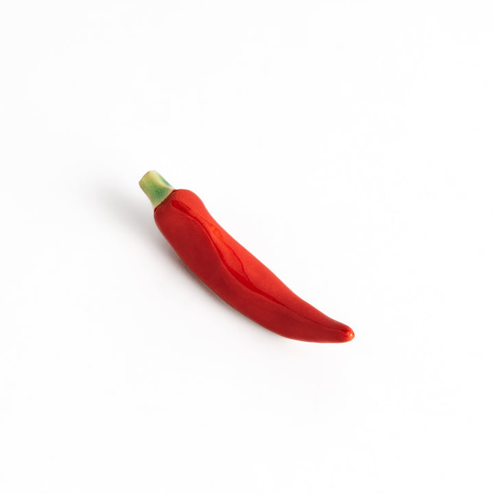 Red chili pepper-shaped chopstick rest with a glossy finish, showcasing a vibrant red body and green stem detail.