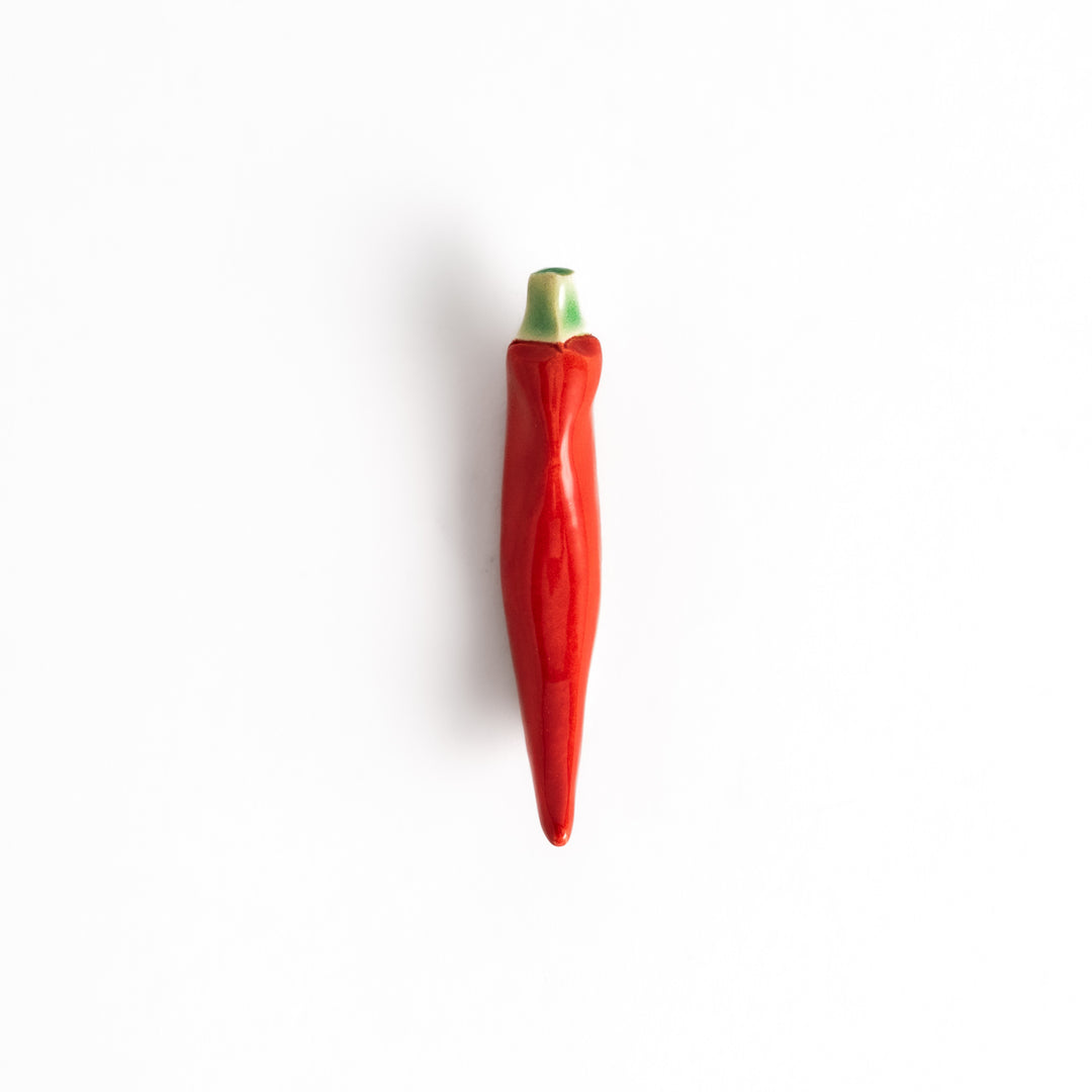 Red chili pepper-shaped chopstick rest with a glossy finish, showcasing a vibrant red body and green stem detail.