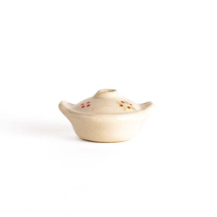 Side view of the earthen pot-shaped chopsticks rest, capturing its lid, floral design, and compact, functional form.