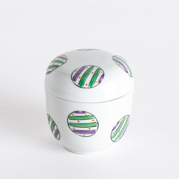 White bowl with a pattern featuring alternating green and purple striped circles on the lid.