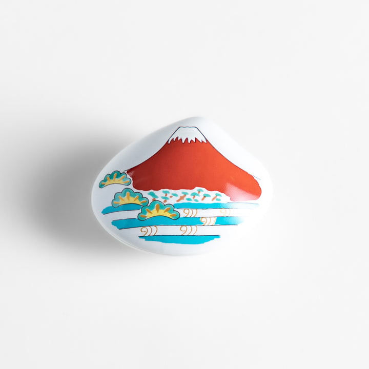 White ceramic incense holder shaped like a seashell, showcasing a striking red Mount Fuji design with golden accents and a secure incense stand inside for refined elegance.