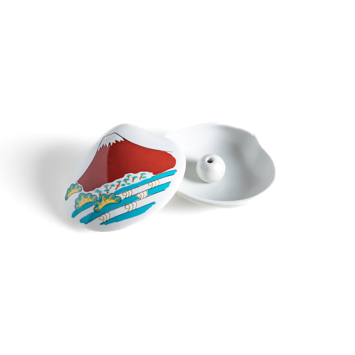 White ceramic incense holder shaped like a seashell, showcasing a striking red Mount Fuji design with golden accents and a secure incense stand inside for refined elegance.