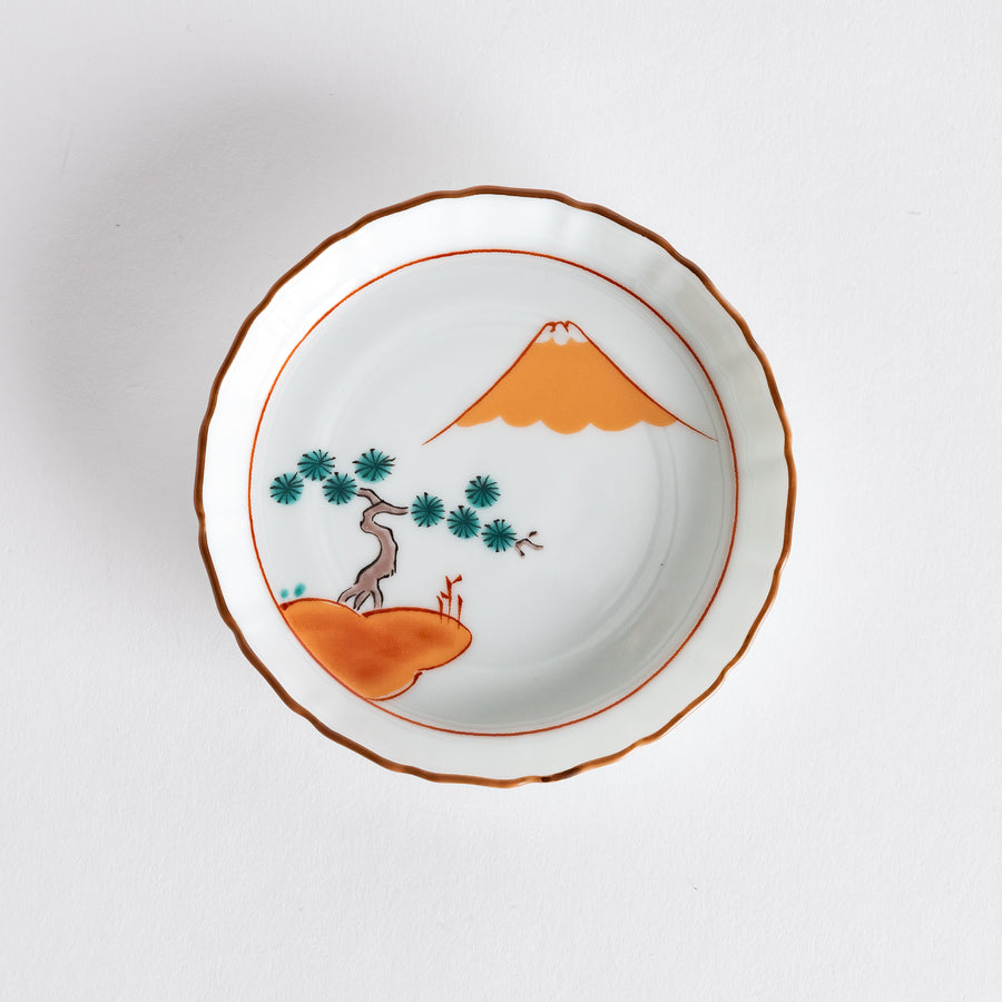 Round ceramic dish featuring a vibrant design of Mount Fuji and a red pine grove, highlighted by a scalloped edge and an orange rim.