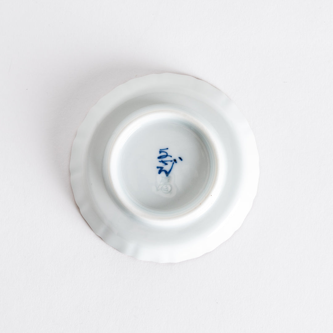 The underside of a round dish, revealing its smooth finish and a decorative blue marking in the center.