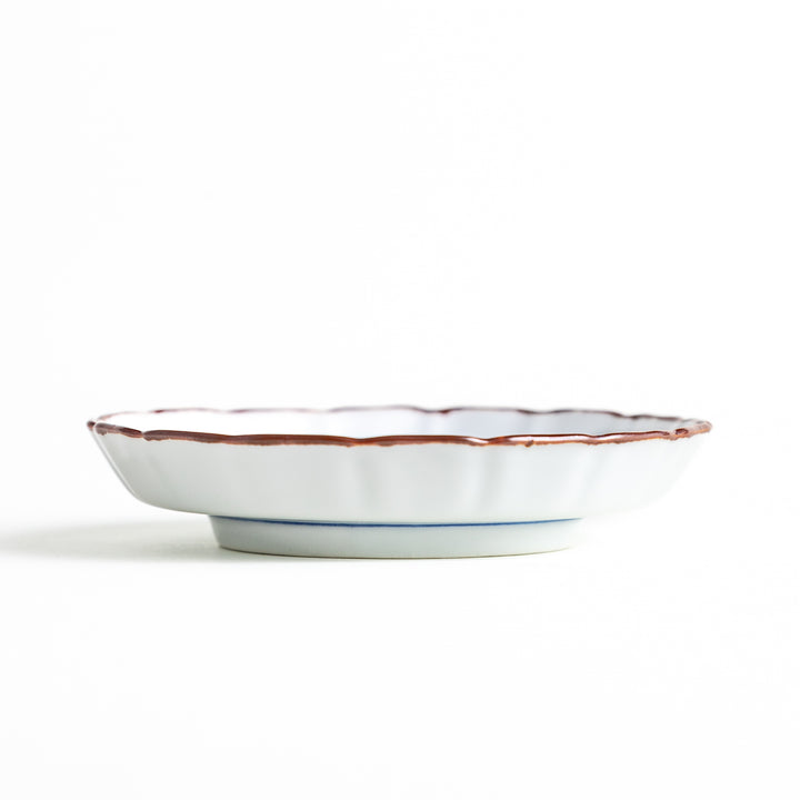 Side view of the porcelain sauce dish, highlighting its low pedestal base and delicate brown-edged raised rim.