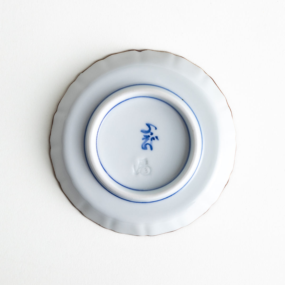 Bottom view of the sauce dish, showing the artist’s mark in blue and the raised base for stability.