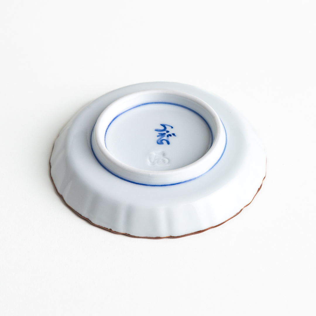 Low-angle view of the sauce dish’s base, displaying its low pedestal design and smooth white porcelain finish with a brown-edged rim.