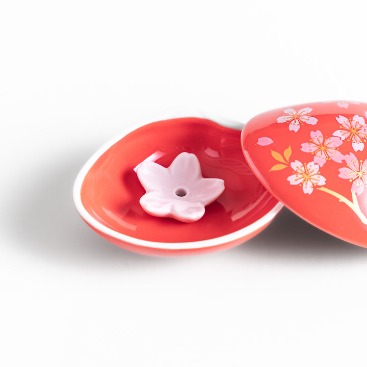 Red sakura shell incense holder with a floral lid and a white cherry blossom-shaped stand, designed to elegantly catch ash while enhancing any space.